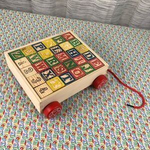 Alphabet Wood Block Pull Cart Toy with Red Wheels.